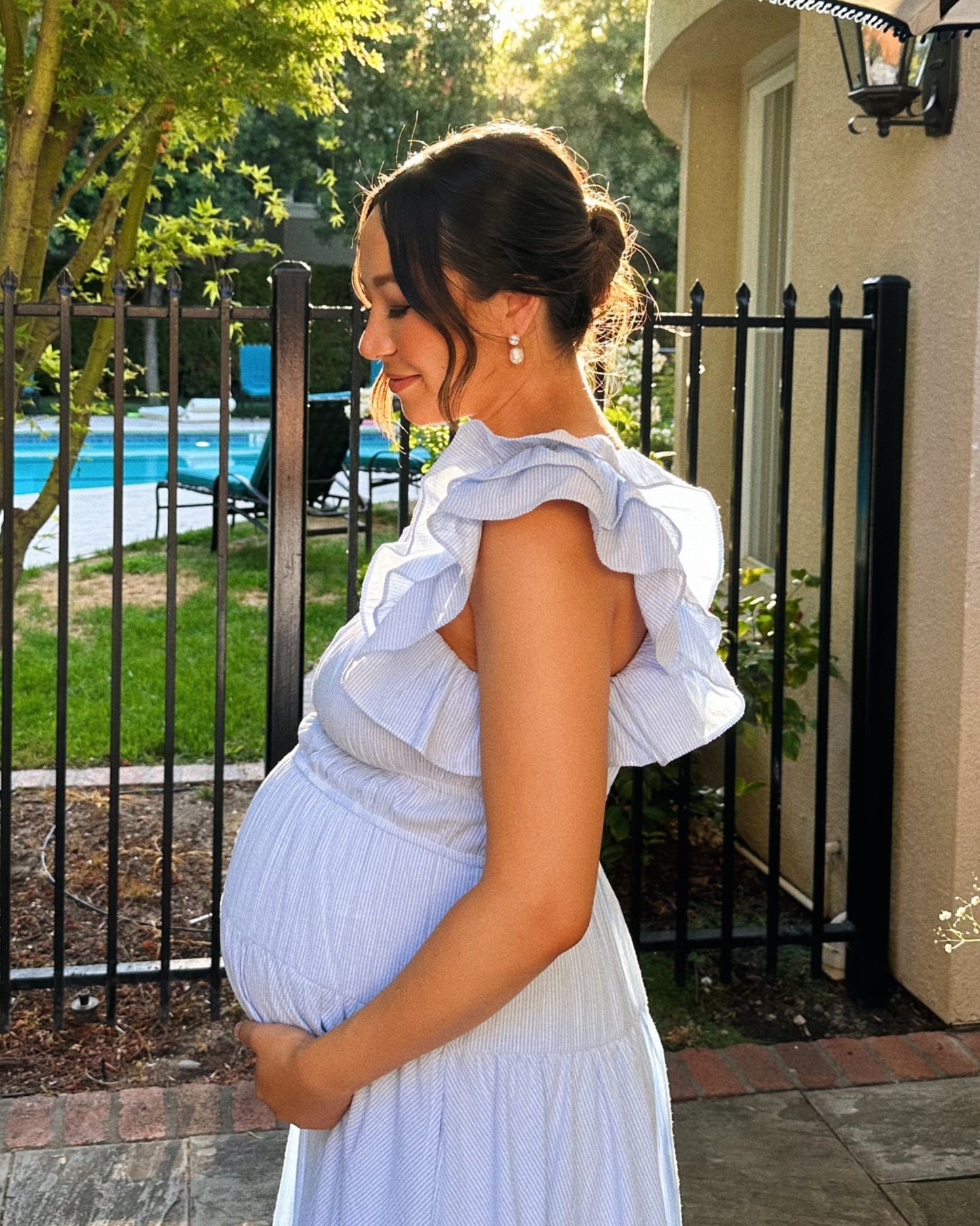 a pregnant mother photographed in the evening sun, with her dark hair pinned into a bun exposes elegant pearl drop earrings similar to teardrop earrings add a timeless look to any occasion - always 18k gold finished for tarnish-free and waterproof jewelry experience