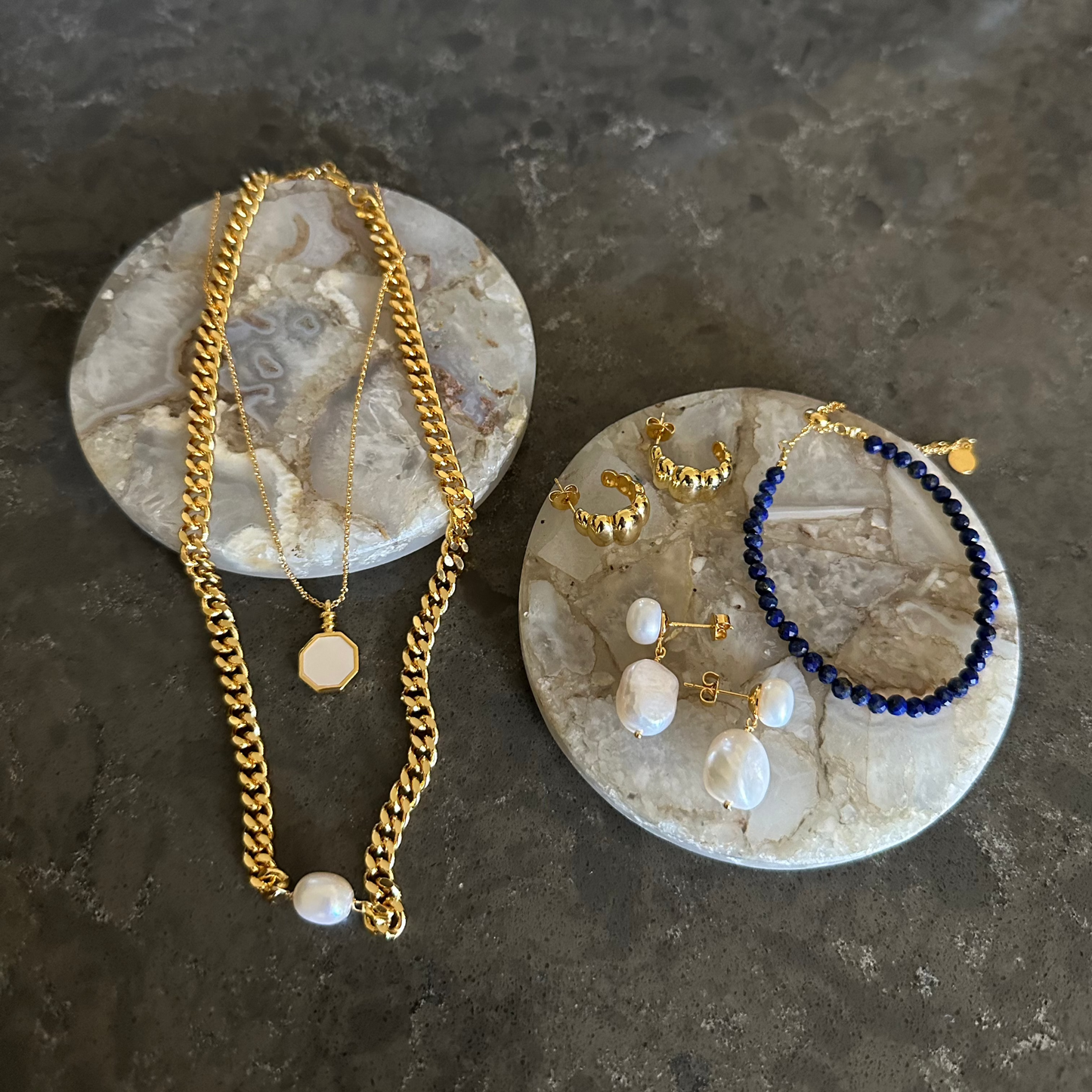 chunky 18k gold plated jewelry displayed on marble countertop, highlighting bright white pearls, pendants and delicate detailed earrings - a gold flat bevelled curb chain