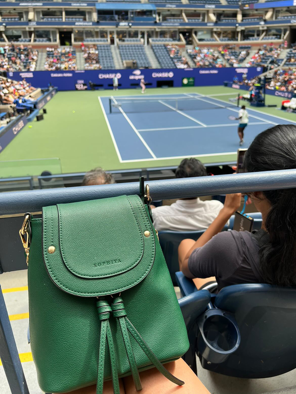 Emerald green small should bag in lap at tennis match