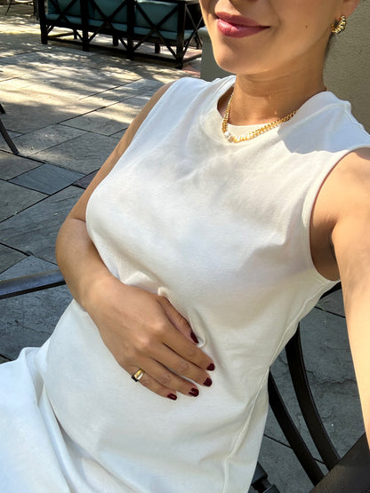 An expecting mother models thick 18k gold plated fine jewelry including necklace and earrings glimmering on a summer terrace