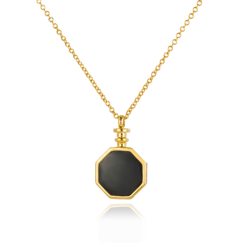 A detailed close up of a gold o-shape chain with octangular pendant in black enamel.