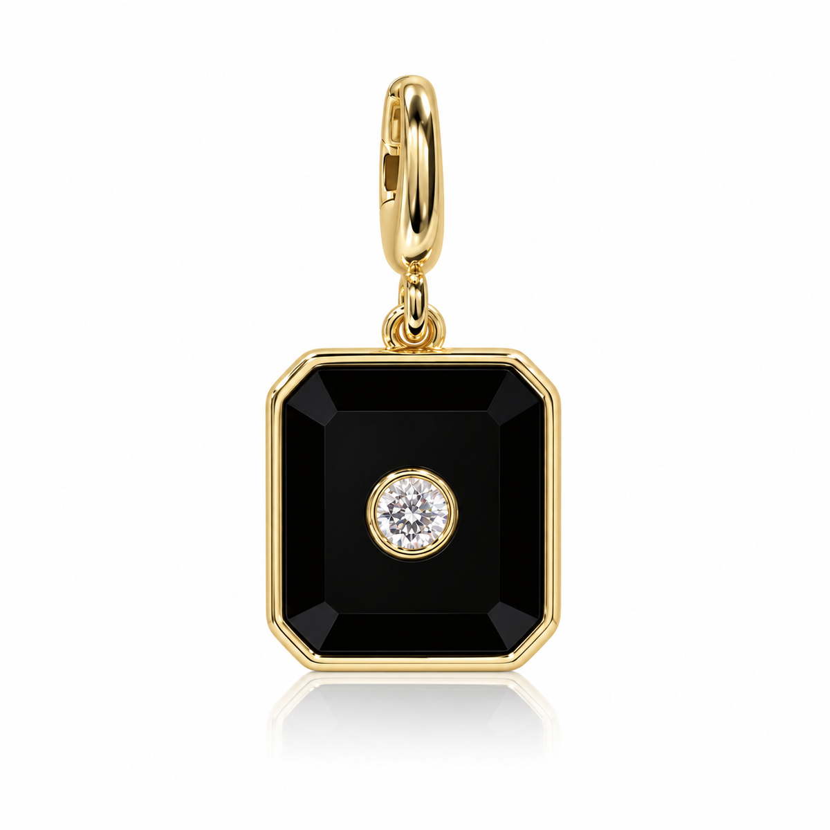 A gold square pendant charm with a black faceted center and a small clear round gemstone in the middle, shown on a white background with a soft reflection.