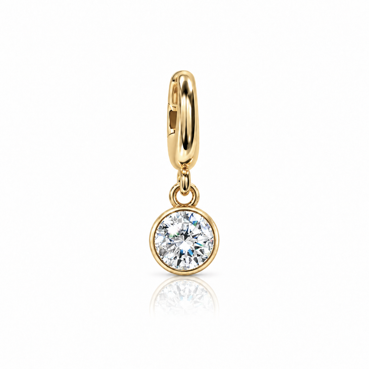 A gold huggie hoop earring with a round bezel-set clear gemstone, shown on a clean white background with a soft reflection below.