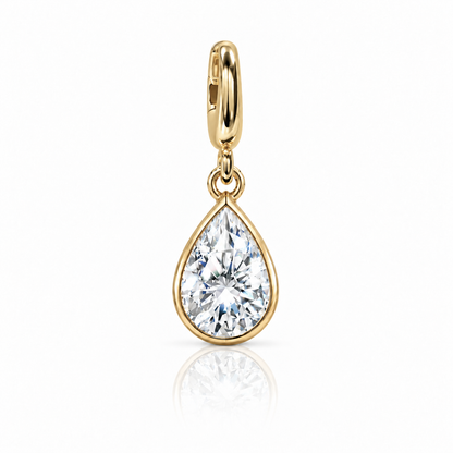 A gold teardrop pendant charm featuring a brilliant-cut clear gemstone in a bezel setting, suspended from a polished gold bail, shown on a white background with a soft reflection below.