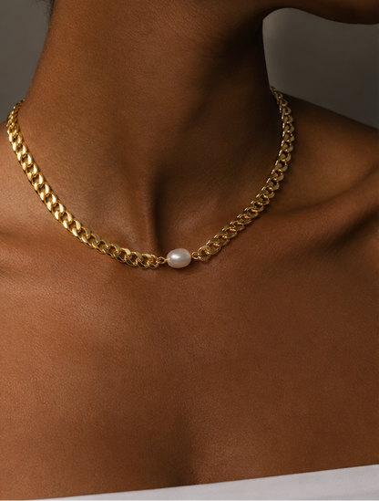 A close-up of a model's neck and collarbone wearing a gold chain necklace with a single white pearl pendant.