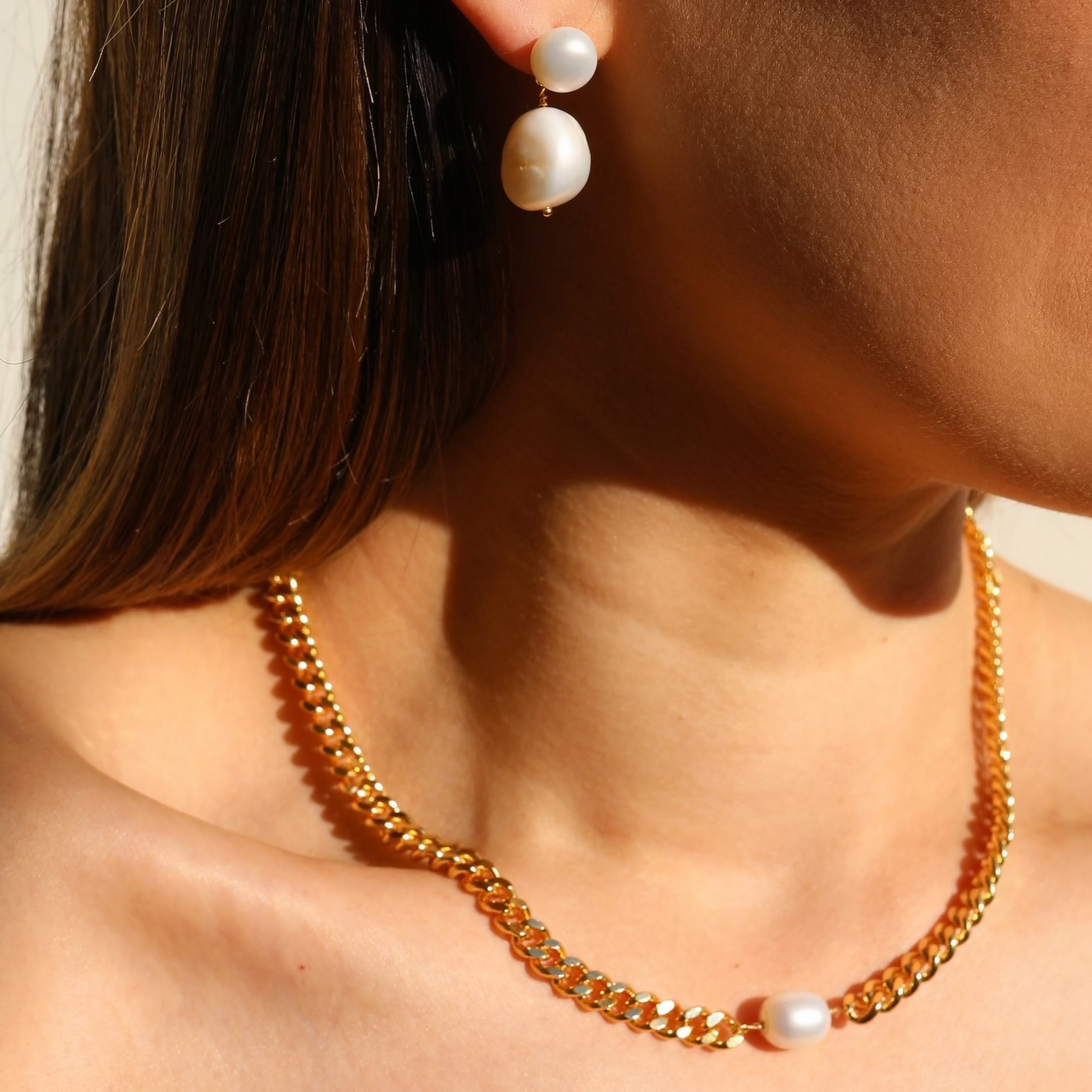 Summer sunset highlights a modeled Liliana Necklace with a thick 18k gold plated flat bevelled curb chain and Charlotte pearl dangle earrings