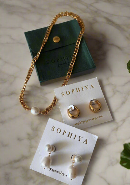 Jewelry spread on marble counter top - Dakota statement huggies, 18k gold hoop earrings, baroque pearl teardrop dangles, elegant classic evening looks, thick flat bevelled curb LIliana chain