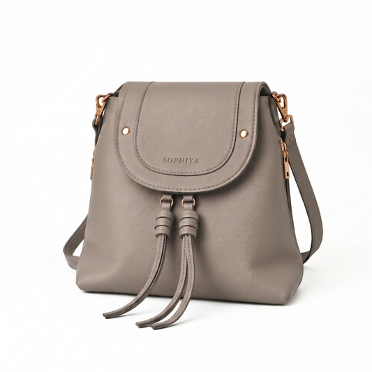 A taupe leather crossbody bag with a flap front, gold-tone hardware, and two hanging leather tassels. The brand name 'SOPHIYA' is embossed on the front flap.