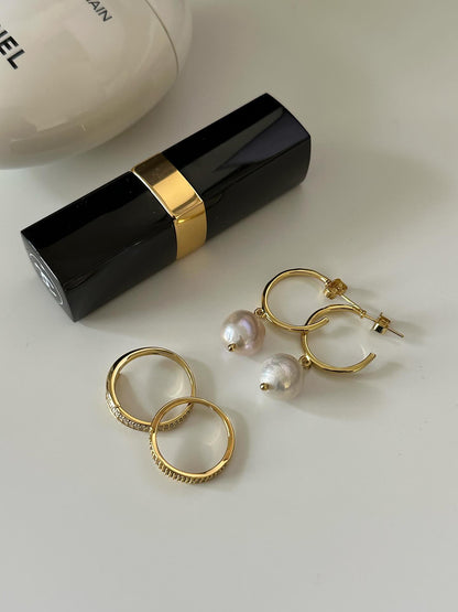 sophiya pearl earrings and gold rings displayed with lipstick and candle on white entryway table