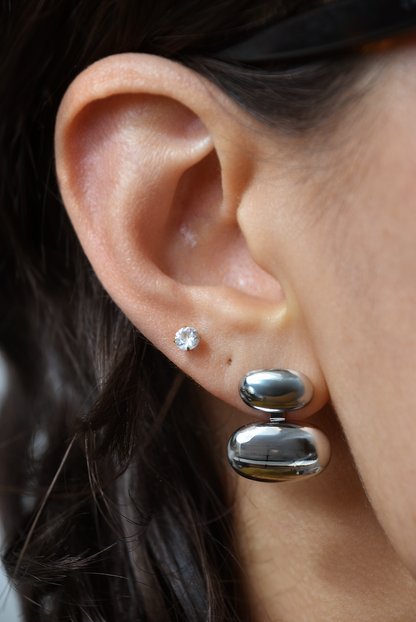 Close-up of an ear wearing silver earrings with a blurred background